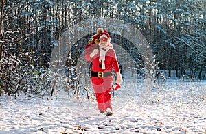 Santa in the winter field. Santa Claus on Christmas Eve is carrying presents to children in a bag full length.
