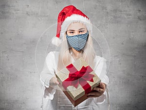 Santa woman giving christmas present box isolated on gray background.Happy young girl holding gift.