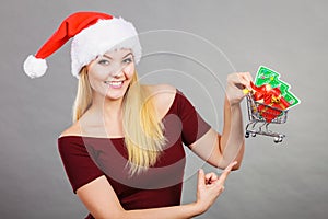 Santa woman holding shopping cart with christmas gifts