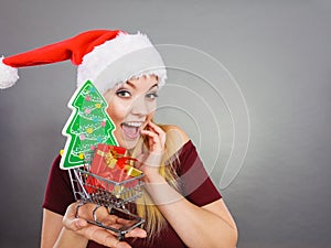 Santa woman holding shopping cart with christmas gifts