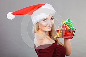 Santa woman holding shopping cart with christmas gifts