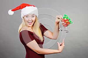 Santa woman holding shopping cart with christmas gifts