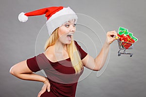 Santa woman holding shopping cart with christmas gifts