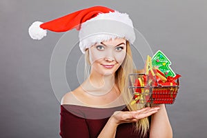 Santa woman holding shopping cart with christmas gifts