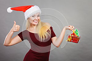 Santa woman holding shopping cart with christmas gifts