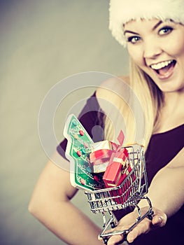 Santa woman holding shopping cart with christmas gifts