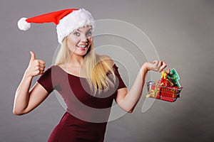 Santa woman holding shopping cart with christmas gifts