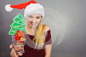 Santa woman holding shopping cart with christmas gifts