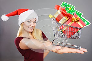 Santa woman holding shopping cart with christmas gifts