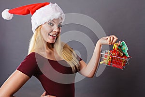 Santa woman holding shopping cart with christmas gifts