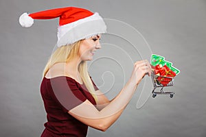 Santa woman holding shopping cart with christmas gifts