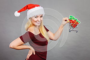 Santa woman holding shopping cart with christmas gifts