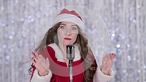 Santa woman sings in a retro microphone . Bokeh background. Close up