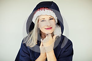 Santas little helper. Beautiful happy senior woman with a santa claus hat, and winter jacket