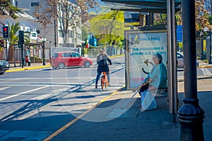 SANTIAGO, CHILE - SEPTEMBER 13, 2018: Unidentified woman waiting the bus in a busstop with some people riding a bike in