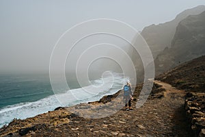 Santo Antao, Cape Verde - Female hiker on trail hike Cruzinha da Garca to Ponta do Sol. Moody Atlantic ocean coastline