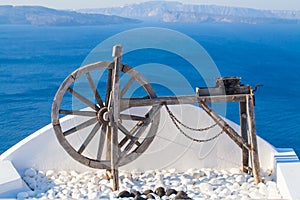 Santorini background card. Wooden wheel against sea