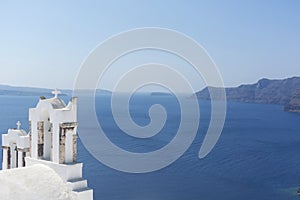 Santorini bell tower of white church in Oia with sea view and volcano, Greece landmark