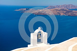 Santorini, Greece. Composition with traditional white architecture and a bell against the backdrop of the blue sea and volcanic