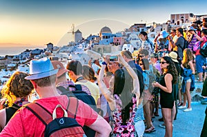 SANTORINI, GREECE - JULY 12, 2014: Tourists enjoy sunset in Oia