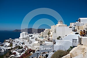 Santorini, Greece. Picturesq view of traditional cycladic Santorini houses on small street with flowers in foreground