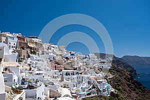 Santorini, Greece. Picturesq view of traditional cycladic Santorini houses on small street with flowers in foreground