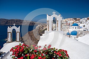 Santorini, Greece. Picturesq view of traditional cycladic Santorini houses on small street with flowers in foreground