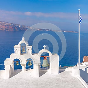 Santorini, Greece. White bell arch and blue sea view with boats. Conceptual composition of the famous architecture of Santorini