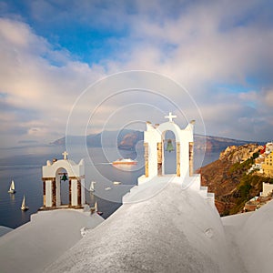 Santorini, Greece. White bell arch and blue sea view with boats. Conceptual composition of the famous architecture of Santorini