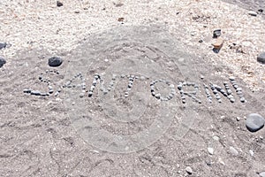 Santorini Island written with stones on the beach sand, in Greece