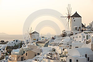 Santorini greek island old town view with white mills and other buildings on sunset.