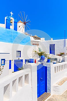 Typical Greek houses and windmill on street of Oia village, Santorini island, Greece