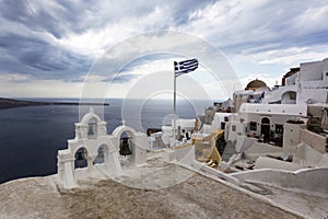 Santorini - Oia, view from the cliff to the caldera. White bell tower on the right and a white roof on the left on the cliff of