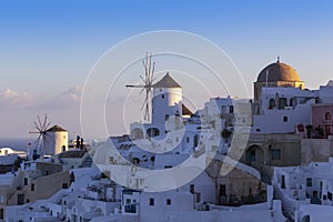 Santorini - Oia, view of white windmills on the slopes of the island. Around are white, picturesque houses between the stone