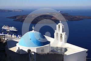 Santorini`s blue dome church and one of the many cruise ships visiting the island. Santorini / Greece - 09/17/2019.