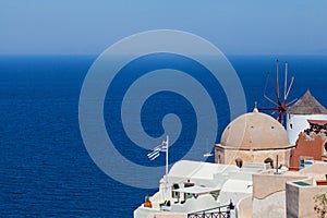 Santorini skyline with Greek flag, sea, blue sky and town. Greece landmark