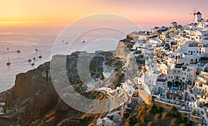 Santorini at Sundown. The famous town of Oia in the sunset. A line of sailing yachts at sea. Romantic holidays. Oia, Santorini,