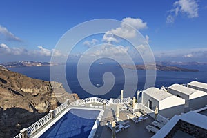 Santorini - View of the caldera from the cliff down to the beautiful pool and white houses. In the background islets and beautiful