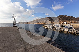 Santorini - the village of Thira, a beautiful bay with a boat harbor surrounded by high rocks. There is a lighthouse at the left
