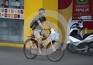 Man in a bike, wearing a mask, gets out of a Drugstore Pharmacy with plenty of medicines