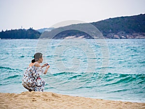 SANYA, HAINAN, CHINA - 4 MAR 2019 - Young Asian Chinese woman tourist snaps a photo at the beach with copy space