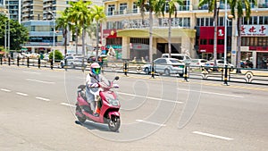 Sanya, Hainan, China - May 15, 2019: Road traffic. A woman rides an electromoped