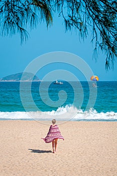 Sanya, Yalong Bay, Hainan, China - May 14, 2019: Beautiful clean beach. A young woman walks along the sandy seashore