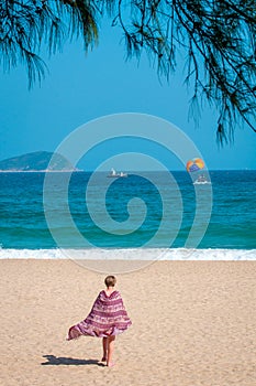 Sanya, Yalong Bay, Hainan, China - May 14, 2019: Beautiful clean beach. A young woman walks along the sandy seashore