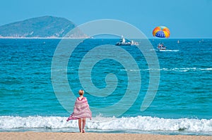 Sanya, Yalong Bay, Hainan, China - May 14, 2019: Beautiful clean beach. A young woman walks along the sandy seashore