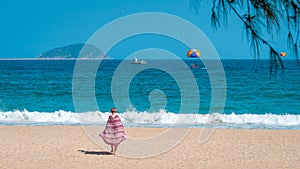 Sanya, Yalong Bay, Hainan, China - May 14, 2019: Beautiful clean beach. A young woman walks along the sandy seashore