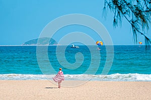 Sanya, Yalong Bay, Hainan, China - May 14, 2019: Beautiful clean beach. A young woman walks along the sandy seashore