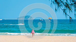 Sanya, Yalong Bay, Hainan, China - May 14, 2019: Beautiful clean beach. A young woman walks along the sandy seashore