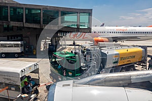 Petrobras Aviation tanker truck with fuel and workers loading luggage in the aircraft yard