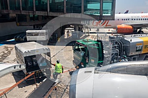 Etrobras Aviation tanker truck with fuel and workers loading luggage in the aircraft yard